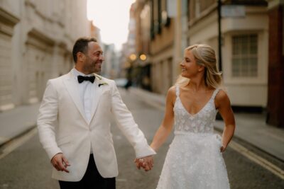 Couple smiling in wedding attire on city street