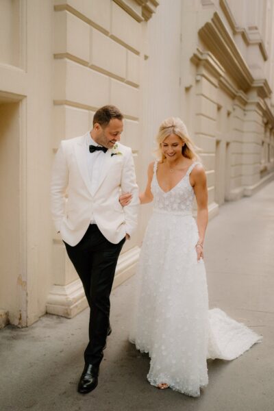 Bride and groom walking together, smiling happily.