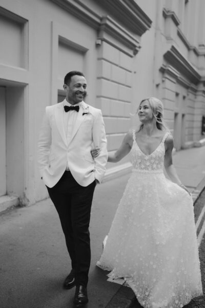 Happy couple walking in bridal attire outside.
