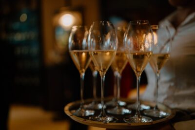 Tray of filled champagne glasses in dim lighting.