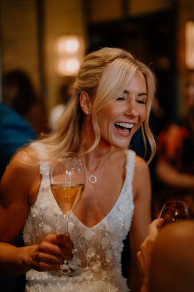Smiling bride holding a wine glass.