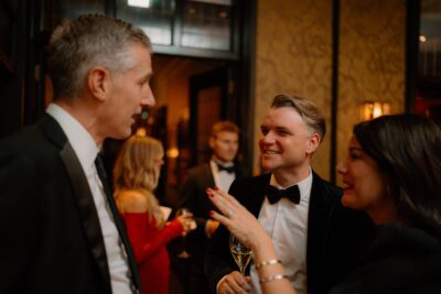 People chatting at a formal event with drinks.