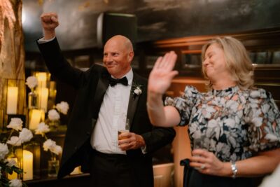 Couple celebrating at formal occasion with raised arms.