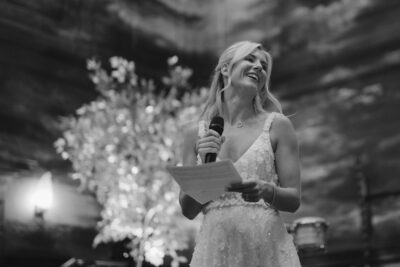 Woman in white dress holding microphone, smiling.