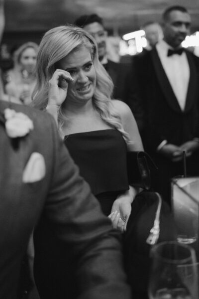 Emotional woman wiping tears at formal event.