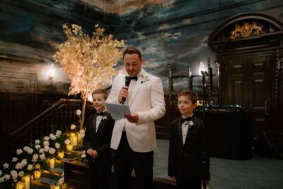 Man and boys in suits speaking at event.