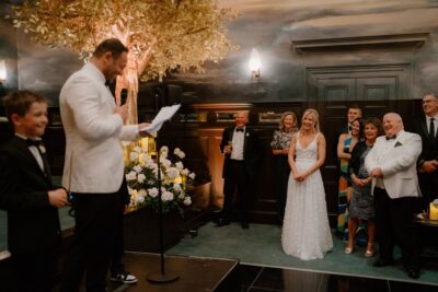 Groom gives speech at wedding reception with guests.