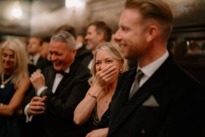 People laughing at formal event in suits.
