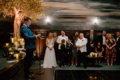 Wedding speech in elegant venue with guests smiling.