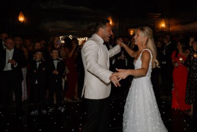 Couple dancing at wedding reception with guests watching.
