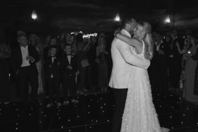 Couple dancing at wedding reception with guests watching.