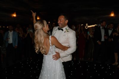 Bride and groom dancing, surrounded by guests.