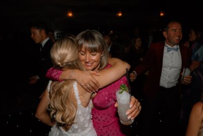 Two women hugging at a lively party.