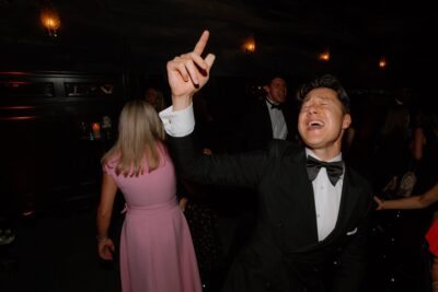 Man in tuxedo dancing joyfully at event.