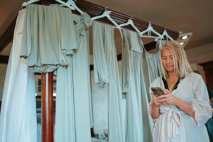 Woman with phone by bridesmaid dresses.