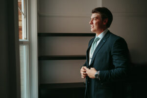 Man in suit looking out window, contemplative.