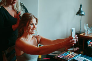 Woman taking selfie during makeup session.