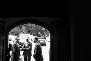 Three men chatting near archway in monochrome.