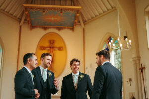Groomsmen chatting in church before wedding ceremony.