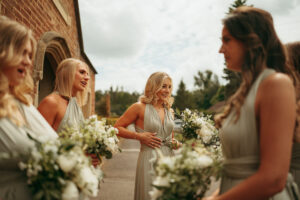 Bridesmaids with bouquets outside church.