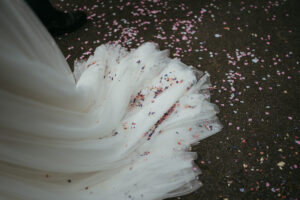 Bridal gown train with confetti on ground.