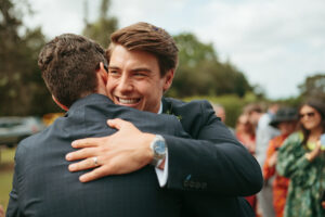 Two men embracing joyfully at an outdoor event.