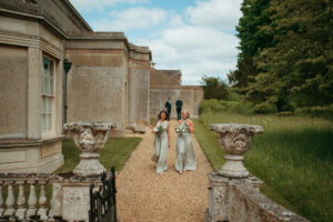 Bridesmaids walking in garden of historic estate.