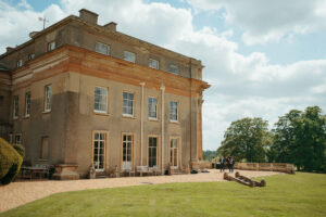 Historic UK country house with people on sunny day.