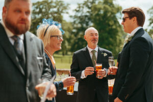 Guests enjoying drinks at outdoor wedding event.