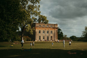Family playing near historic countryside mansion.