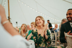 Guests laughing at wedding reception under string lights.