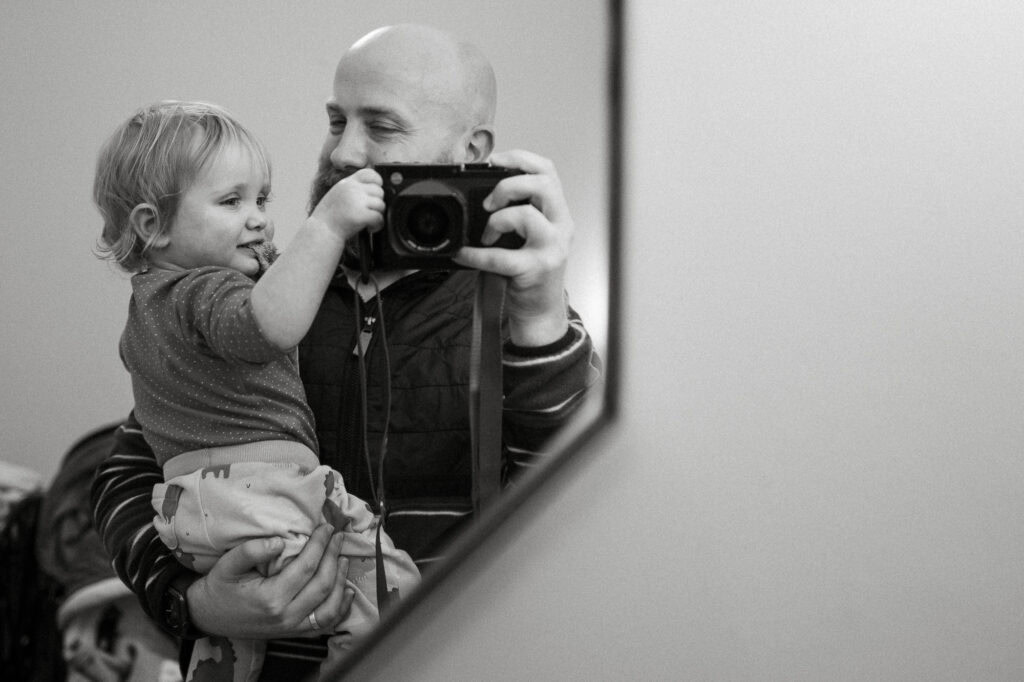 Father and child taking photo in mirror.