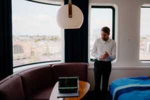 Man in hotel room with city view.
