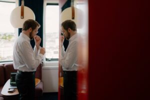 Man in office adjusting cufflinks, city view background.