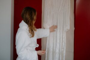 Person admiring a white dress in dressing gown.