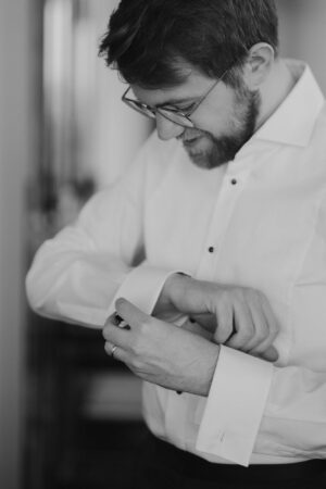 Man fastening shirt cufflinks, preparing for event.