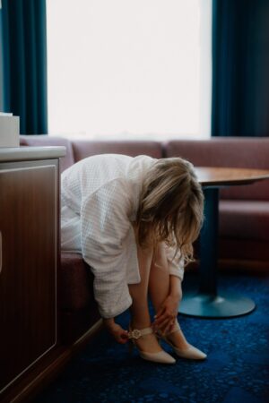 Woman fastening shoes in hotel room.