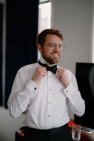 Man adjusting bow tie in formal attire.