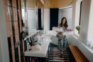 Woman carrying flower trays in stylish bathroom.