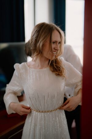 Woman smiles in elegant, sequinned dress.