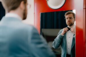 Man adjusting bow tie in mirror reflection
