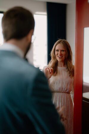 Woman smiling in doorway, greeting a man.