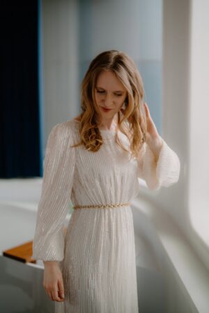 Woman in elegant white dress by window