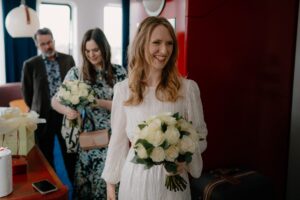 Bride holding bouquet, smiling indoors before wedding.
