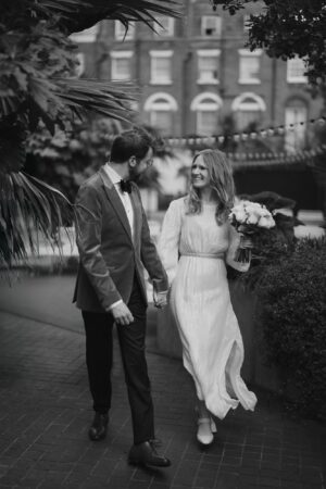 Smiling couple holding hands, wedding day stroll.