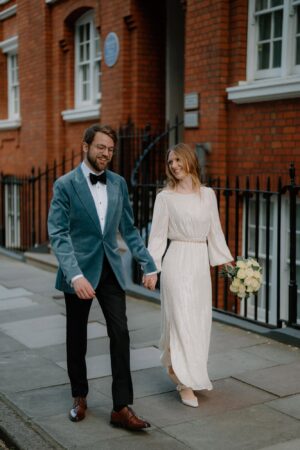 Couple walking hand in hand, elegant outfits.