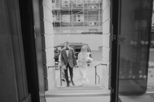 Couple in wedding attire entering building