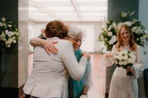Joyful wedding embrace with bride holding bouquet.