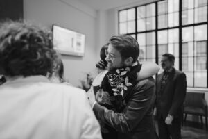 People hugging at indoor gathering, black and white