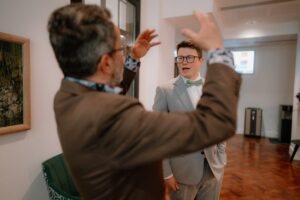 Two men in suits having a conversation indoors.
